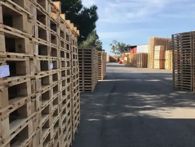 Calle entre pilas de palets en el patio de la fábrica