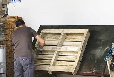 Operario reparando un palet de madera en el taller